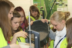 Die M&auml;dchen f&uuml;llen zum Deichbau groben Sand in die Versuchsrinne